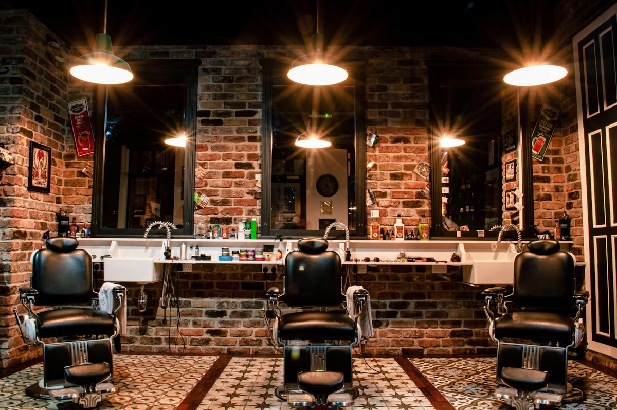 Interior de una barbería con sillones de piel y pared de ladrillo